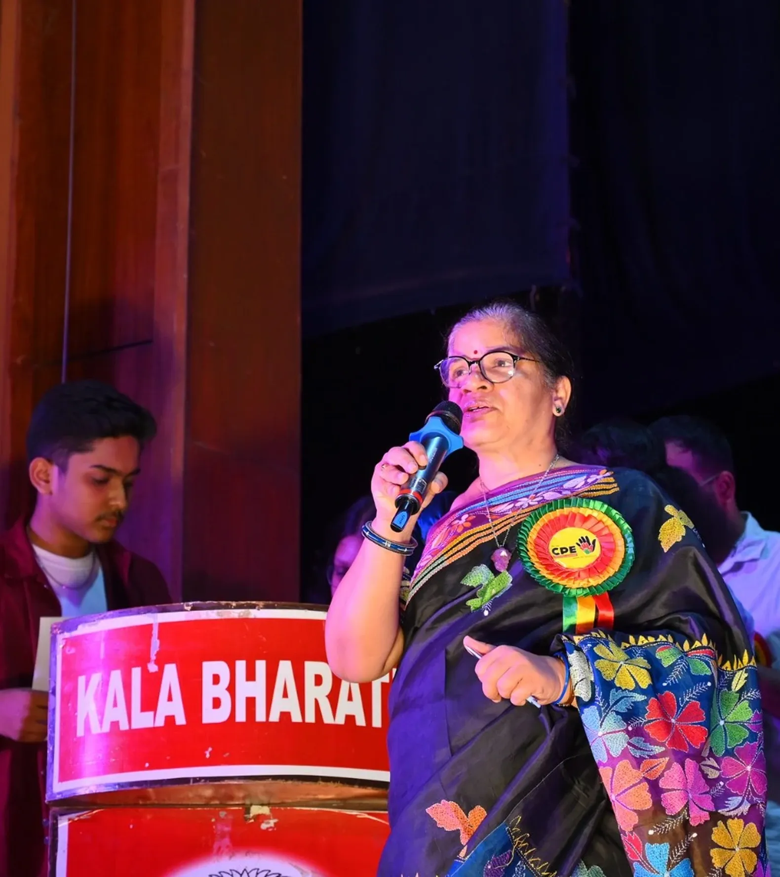 A faculty member addressing the Annual Day audience at the podium