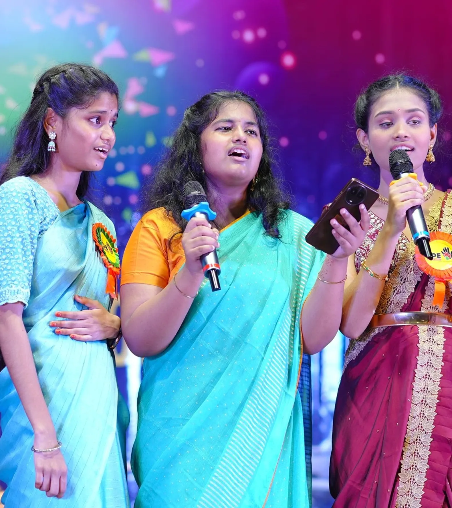Three students singing together during the Annual Day celebrations